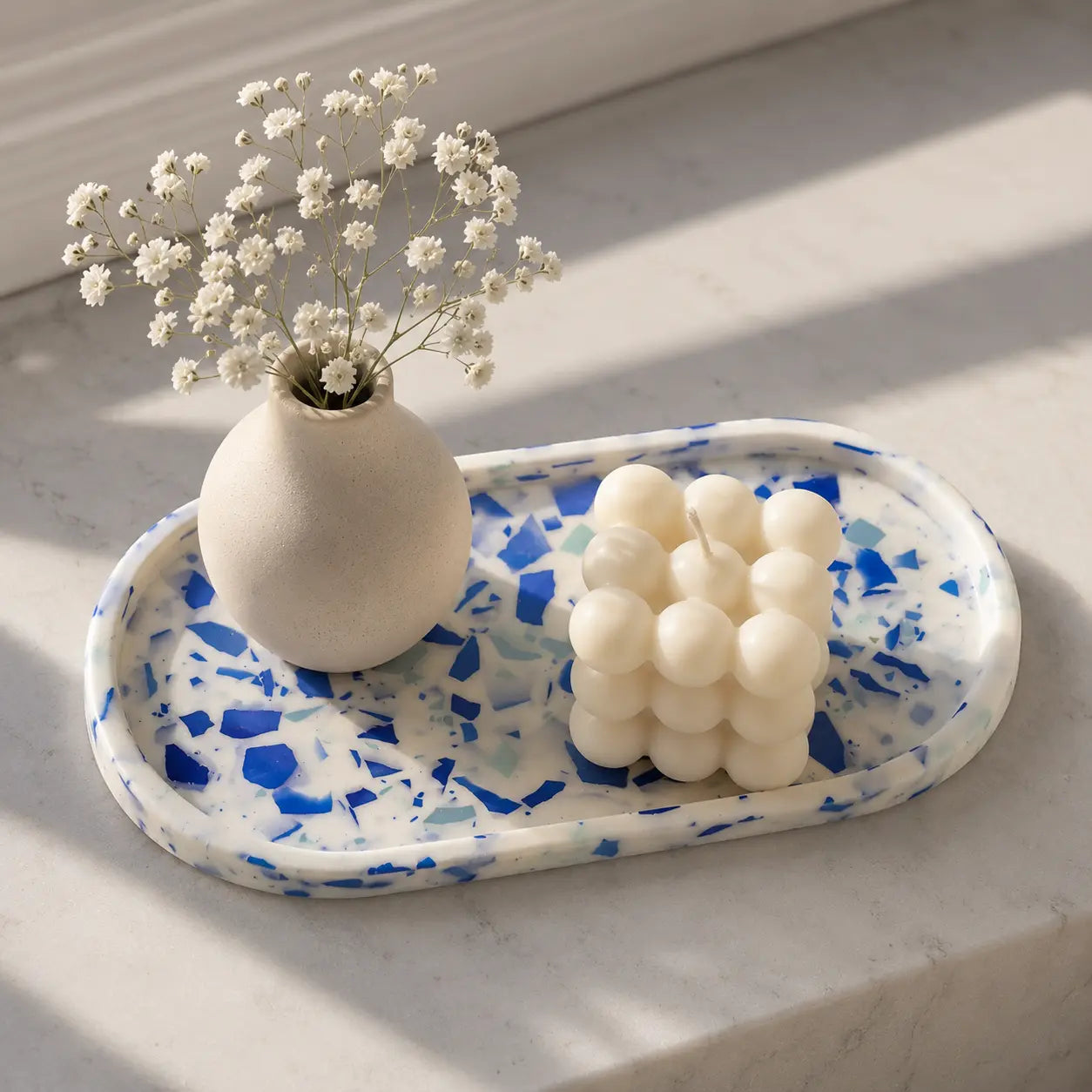 Blue terrazzo decorative tray with bubble candle and small flower vase