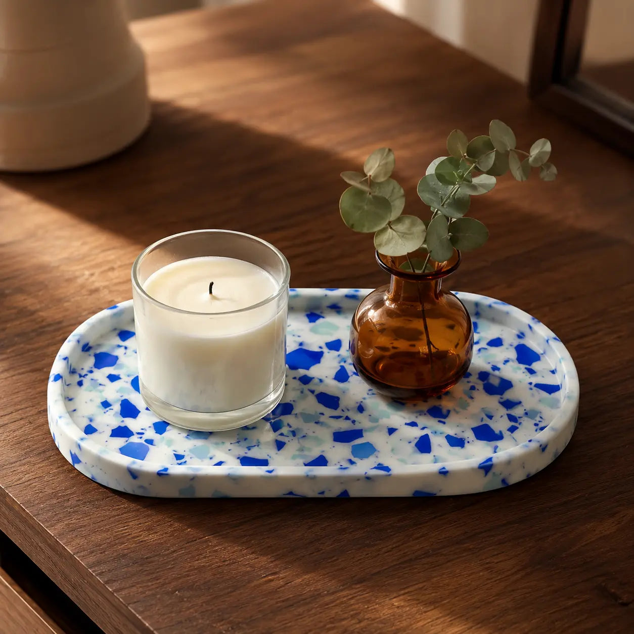 Blue terrazzo tray styled with candle and small vase on wooden table