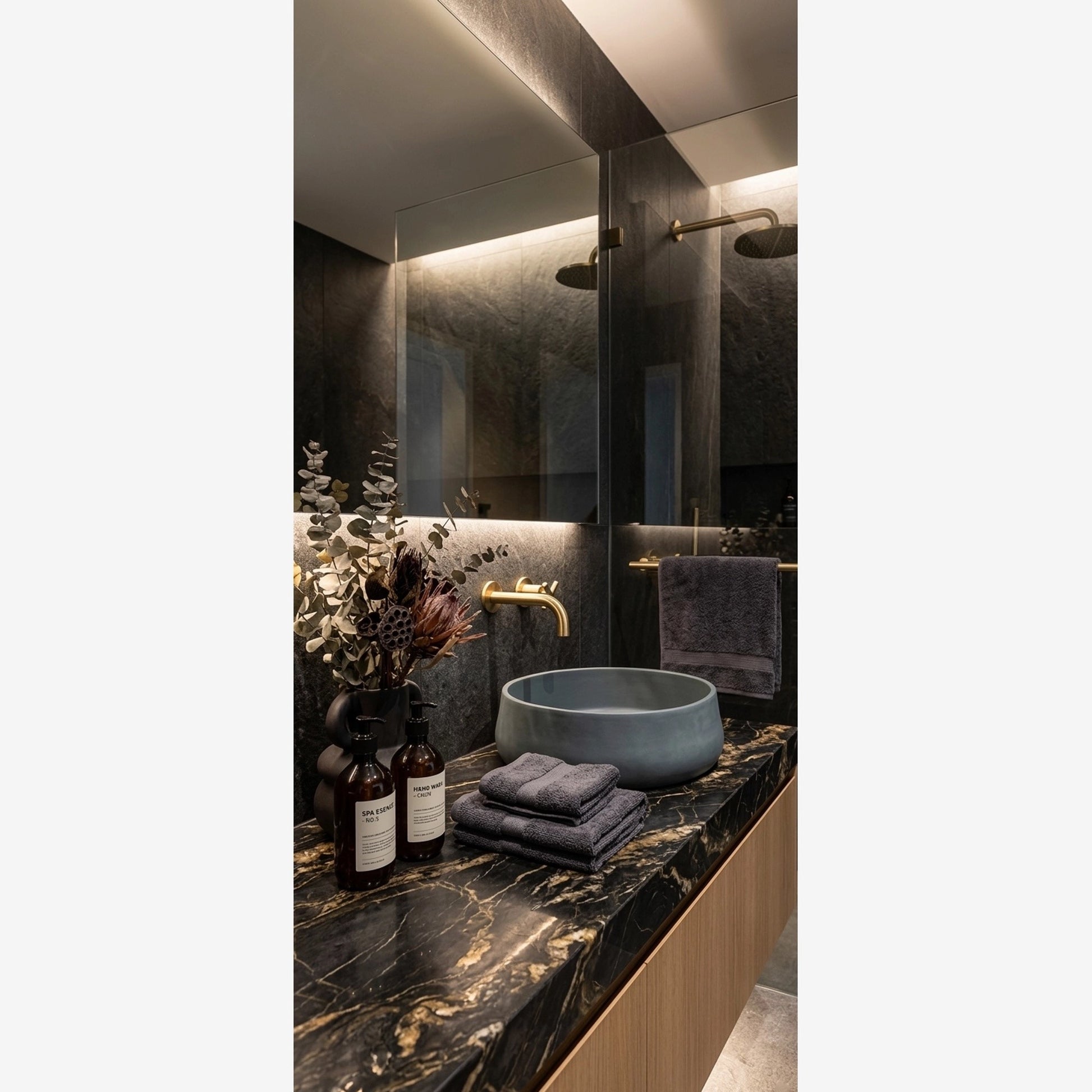 Concrete stone vessel sink in luxury modern spa bathroom interior with dark marble vanity and brass faucet