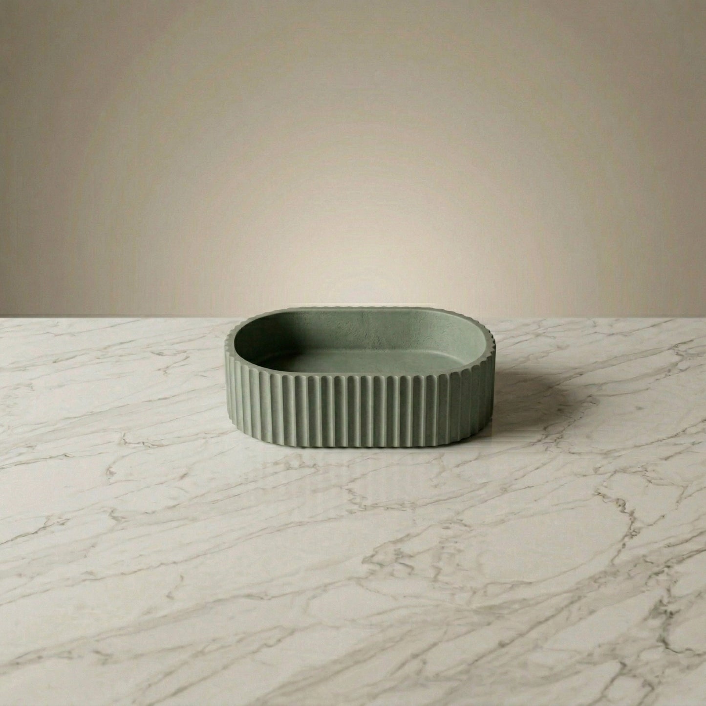 A sage green fluted vessel sink made from stone composite material, featuring an oval shape and minimalist organic modern design. Perfect for luxury, spa-inspired and contemporary bathrooms. Ideal as a statement countertop basin for modern home decor interiors.