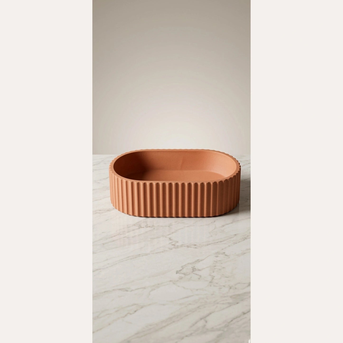 Terracotta fluted oval vessel sink on marble surface