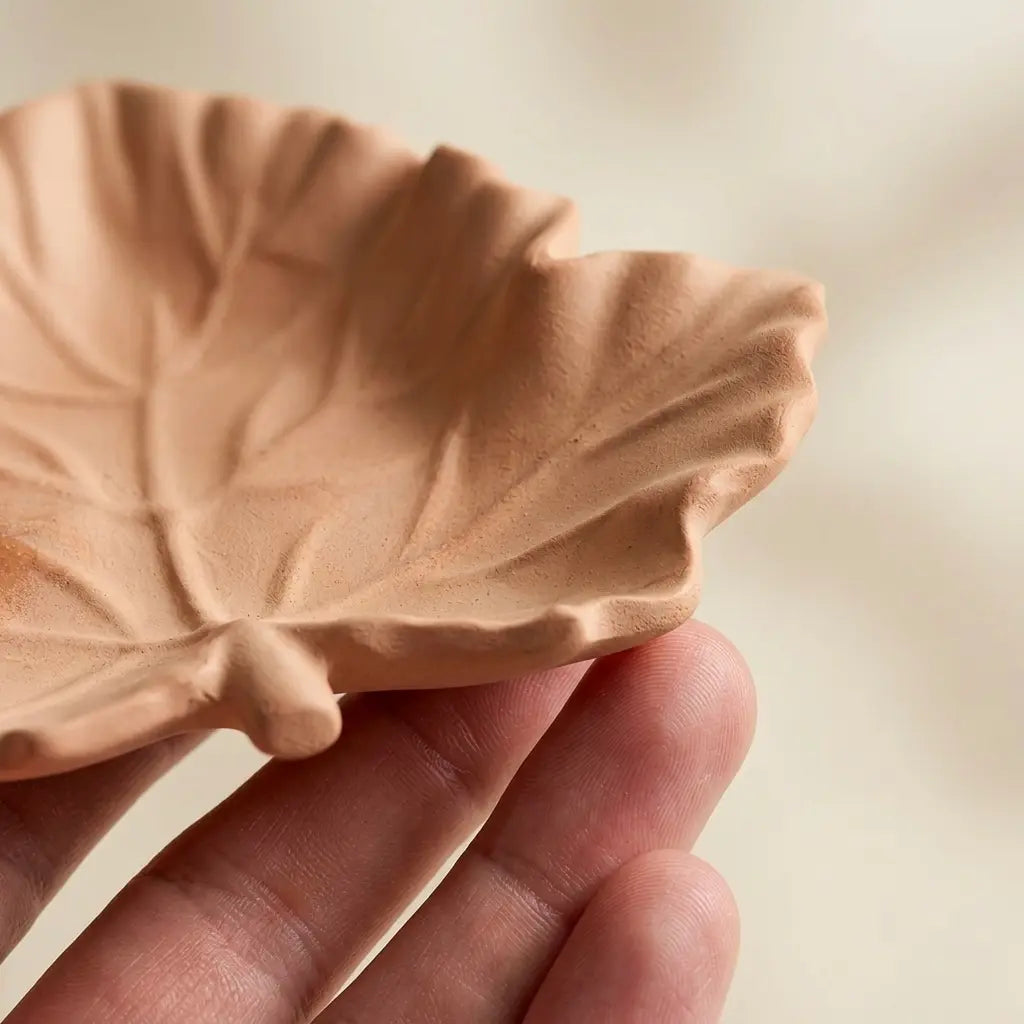 Close-up of terracotta leaf ring dish showing raised vein detail and curved sculptural edge